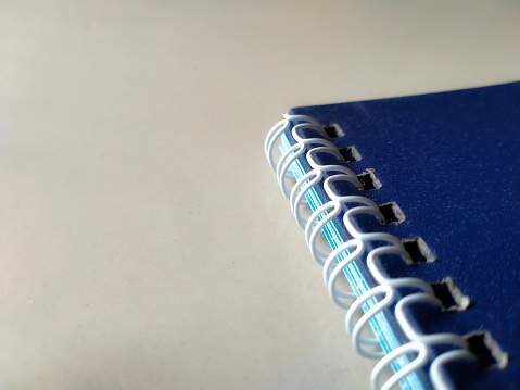 A blue notebook with its ring binder on a white background
