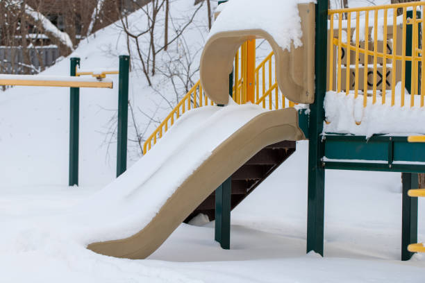 Slide covered with snow at playground in park with in winter after snowfall
