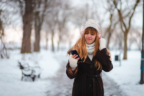 istock Happy young woman taking a walk in a public park while it's snowing 1952682097