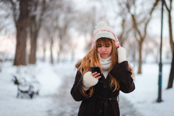 istock Happy young woman taking a walk in a public park while it's snowing 1952682099