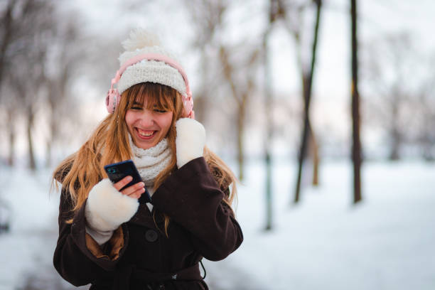 istock Happy young woman taking a walk in a public park while it's snowing 1952682651