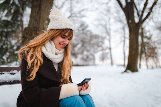 istock Happy young woman using her smartphone while sitting on a bench in a public park 1952683737