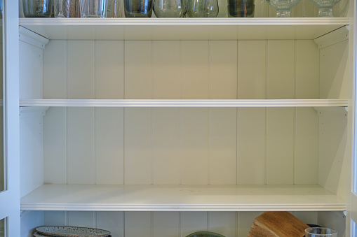 Empty shelves of the kitchen cabinet without dishes and plates