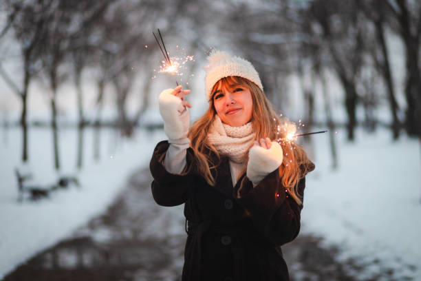 istock Smiling young woman holding sparklers outdoors during winter 1952689741