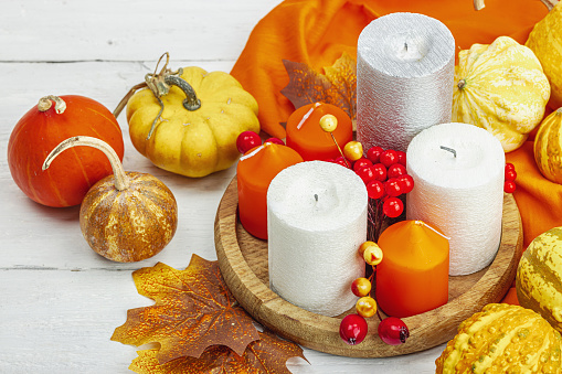 Autumn cozy composition. Pumpkins, candles, leaves, berries. Traditional fall decor, seasonal good mood. Flat lay, white wooden background, close up