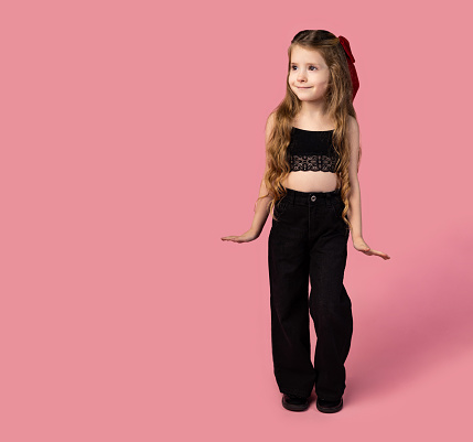 Full length happy little caucasian kid school girl 6-7 year old in casual denim black clothes, isolated on pink background Childhood education concept. High quality photo
