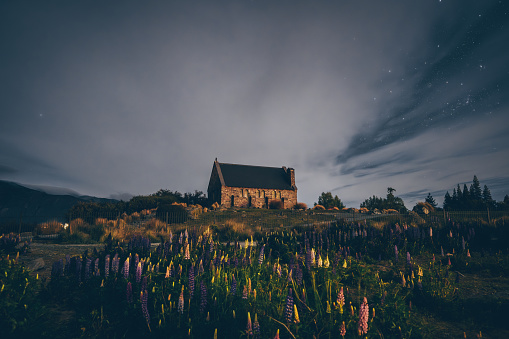 Experience the mesmerizing beauty of New Zealand's Church of the Good Shepherd under a starry night sky. A celestial spectacle awaits.