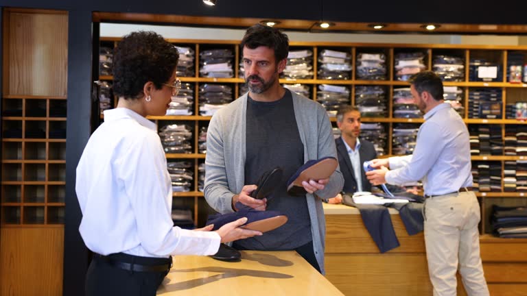 Saleswoman showing options of luxury shoes to male customer at a men’s boutique