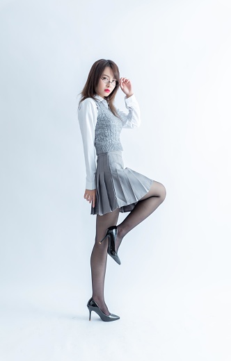 Asian school girl in grey skirt and white blouse posing