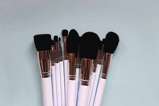 Various make up brushes on bright blue background. Top view.