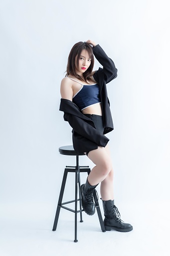 A young woman in a blue sports bra and black shorts poses on a stool