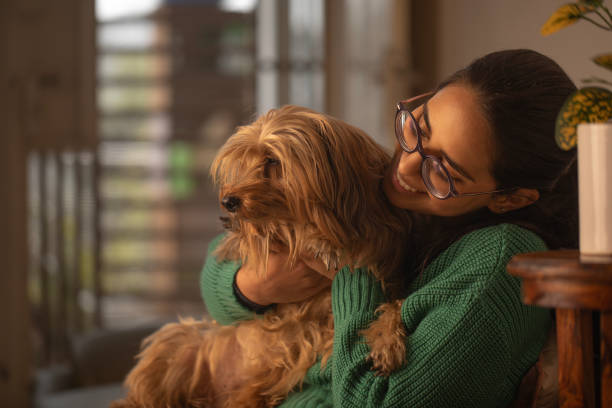 istock Smiling woman embracing dog on sofa 1952746071