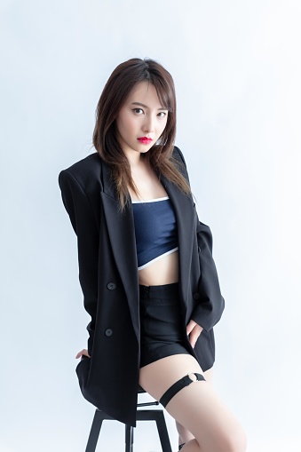 Elegant Asian woman in black suit and blue sports bra sitting on chair