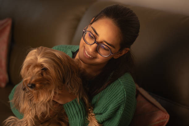 istock Smiling woman embracing dog on sofa 1952747412