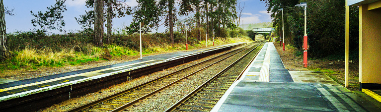 A station England UK. Diesel powered railway line in the English countryside. Station on a sunny day. Panoramic - Panorama.