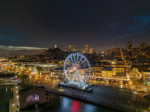 An aerial view of the Sky Star Ferris Wheel along  Fisherman's Wharf in the early morning. San Francisco skyline in the background.