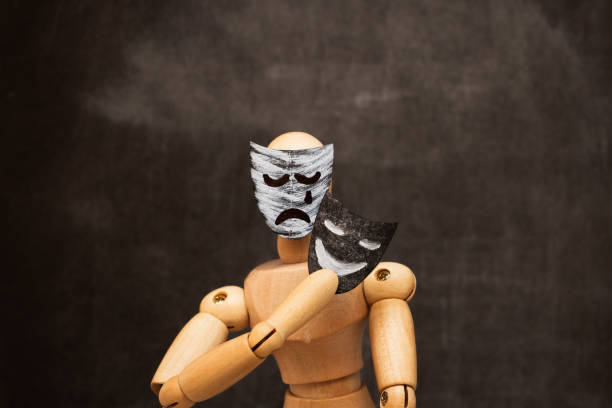 istock Sad wooden man putting on a smiling mask. 1952798533