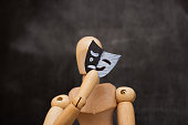 Wooden man putting on mask with smile and sadness, concept of bipolar disorder.