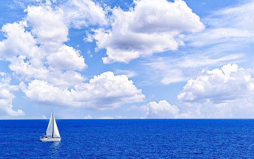 Boat, sailboat sailing on the beach of Mallorca under a blue sky with white clouds