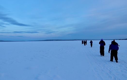 People walk on a frozen lake in Meltosjärvi in Lapland, in the Arctic Circle