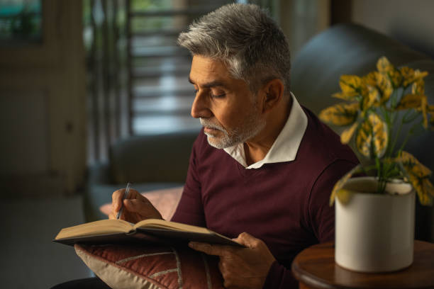 istock Old male author writing book on sofa at home 1952845133