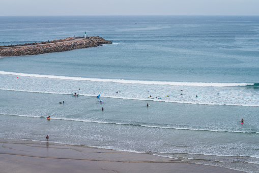 Rabat, Morocco - December 31, 2023: People Surfing in the ocean at the mouth of the Bou Regreg river from the Atlantic Ocean.