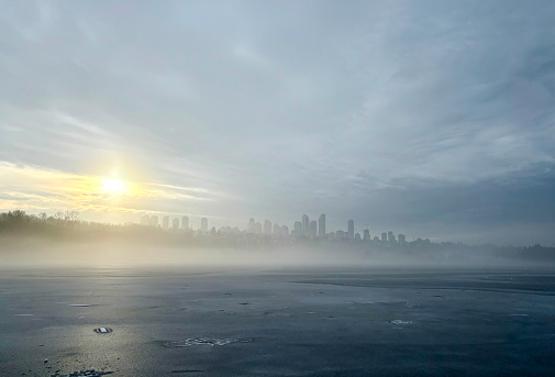 Looking out at the Metrotown district on a foggy winter day from across and icy Deer Lake in Burnaby, B.C.
