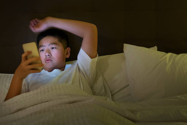 istock Teenage boys using mobile phone in bed 1952853676