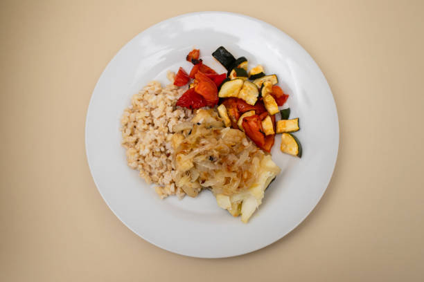 istock fried cod fish with onion, vegetables, rice and olive oil on plate 1952874812