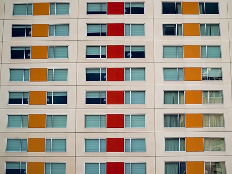 Alternating yellow and red squares on three columns of windows of an apartment building.