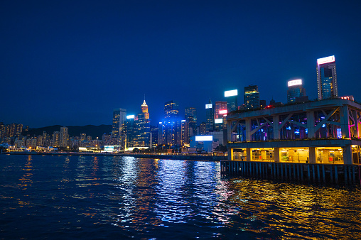 Aerial view over Victoria Harbour at night, from the glittering skyscrapers of Wan Chai and Central across the busy waterway to the crowded high-rises of Kowloon and Mong Kok in the heart of Hong Kong, China.