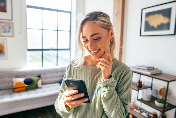 Millennial woman using smart phone at home. Blonde woman using mobile app on mobile device