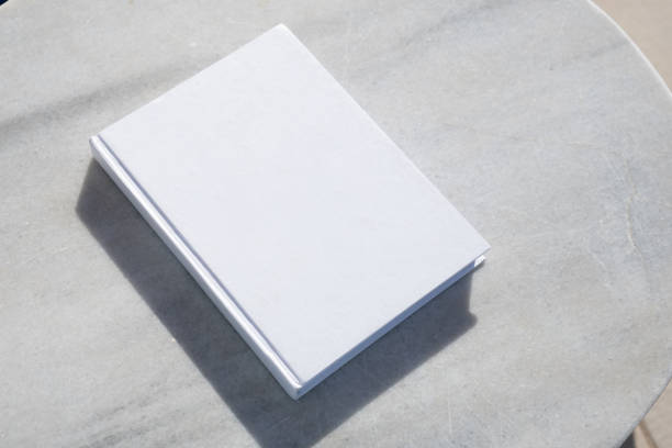 reading at vacation. blank book for mockup design on marble table by the swimming pool