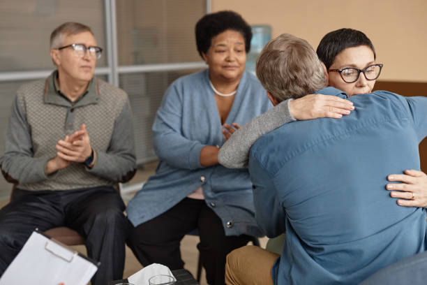 istock Two Senior People Embracing in Group Therapy Session 1952993163