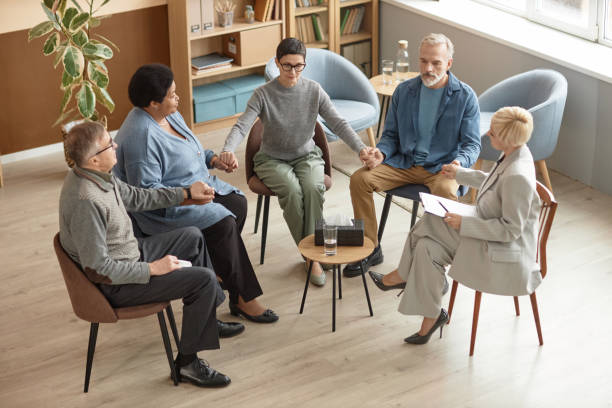 istock Senior People Holding Hands in Therapy Session 1952993551