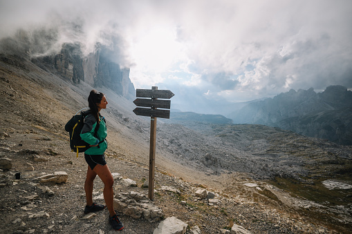 Female hiker enjoys the beautiful outdoors, walking on top of the Tre Cime di Lavaredo, admiring the view.