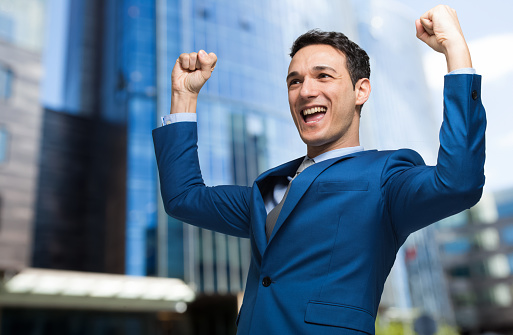 Handsome businessman raising arms in sign of victory