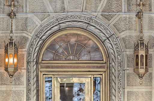 ornate building entrance detail with arched doorway and gold metallic lanterns (brick residential building in the style of urban theater in brooklyn new york) apartment complex condominium co-op