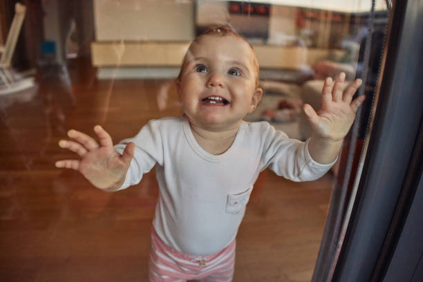 little smiling baby lying on a blanket putting her feet in her mouth due to discomfort caused by teething. concept of the emergence of the first teeth in the childhood stage