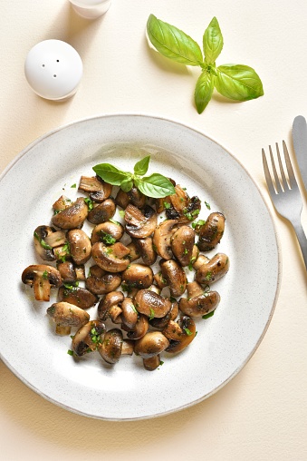 Stewed mushroom with greens and spice on plate over light stone background. Vegetarian vegan or heatlhy diet food concept. Top view, flat lay
