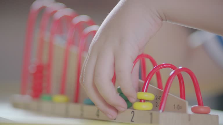 A little boy playing with a colorful abacus in the living room at home.