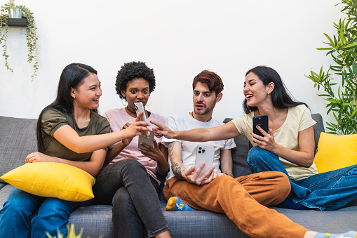 A close-knit group of friends engaging with each other's phone content, enjoying a social tech experience