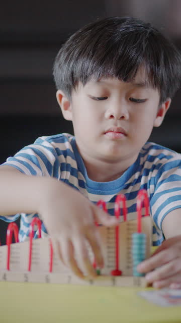 A little boy playing with a colorful abacus in the living room at home.