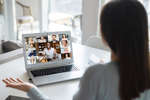 Female freelancer talking online with group of diverse colleagues or classmates, woman participates in video conference with multiracial team, virtual meeting on the laptop, e-learning