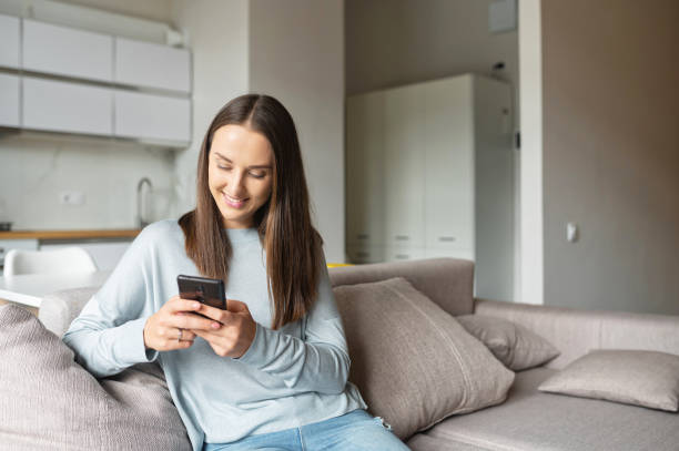 istock Smiling and positive young woman using smartphone 1953116469
