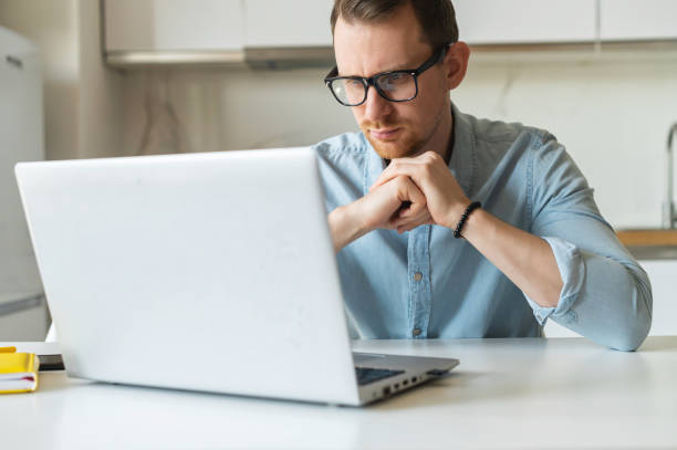 istock Focused young businessman using laptop for remote work from home 1953116493