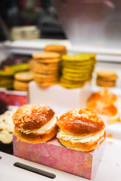 Cream-filled pastries topped with almond flakes on a pink pastry stand.