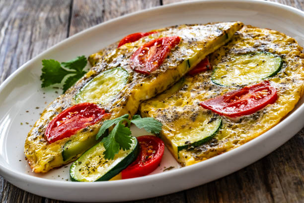 istock Omelet - scrambled eggs with cheese, zucchini and tomatoes on wooden table 1953155766