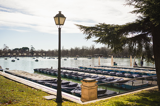 Boats line the edge of the grand lake in Madrid's Retiro Park under a lamp post on January 20, 2024, in Madrid, Spain