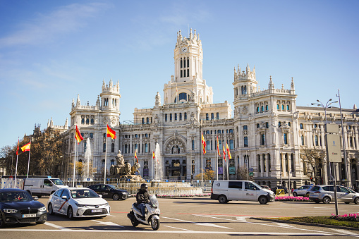 The Cybele Palace in Madrid, framed by Spanish flags, under a clear blue sky on January 20, 2024, in Madrid, Spain